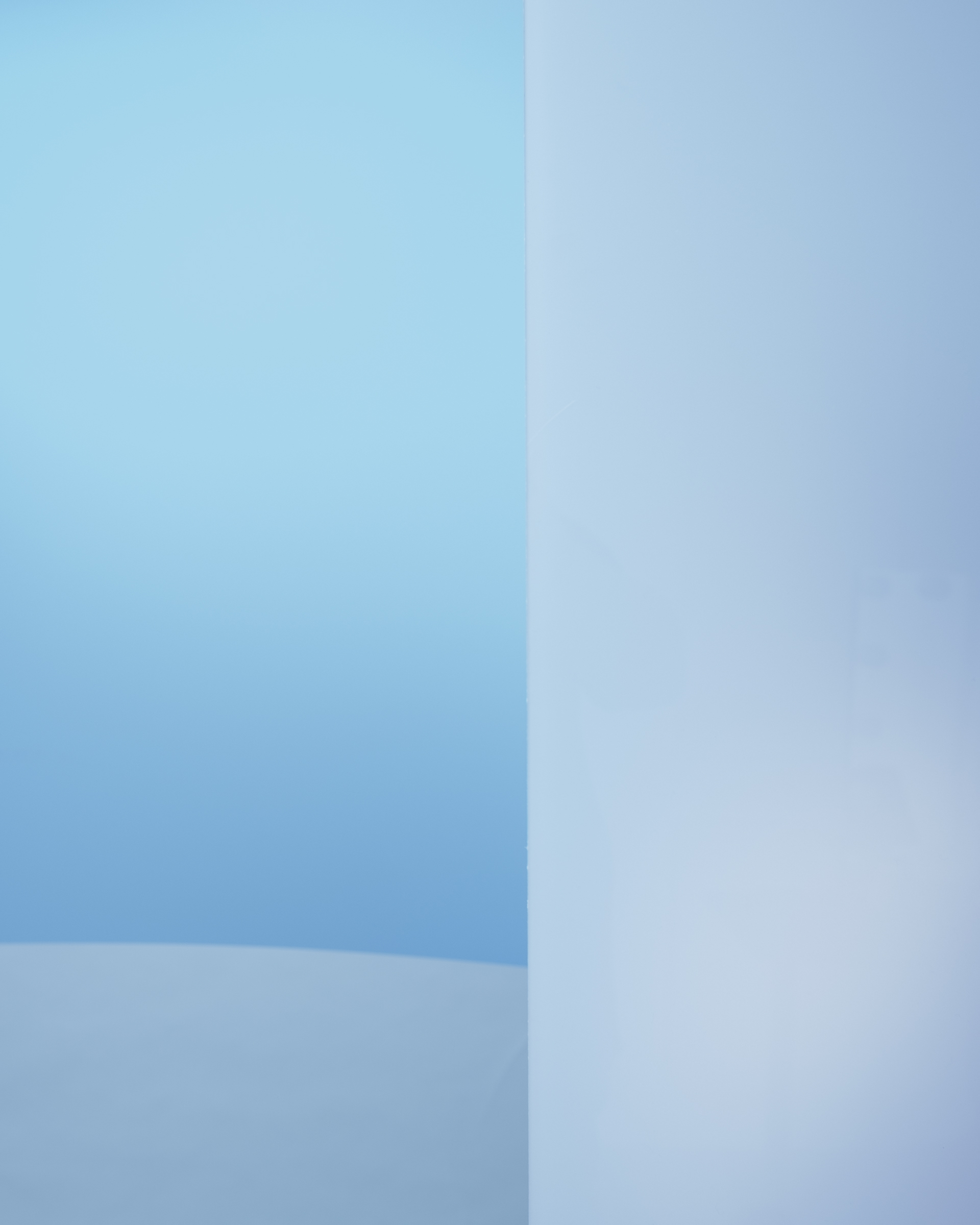 Minimalist blaue Szene mit einem sanft gewölbten Boden und einer vertikalen Wand im Vordergrund.