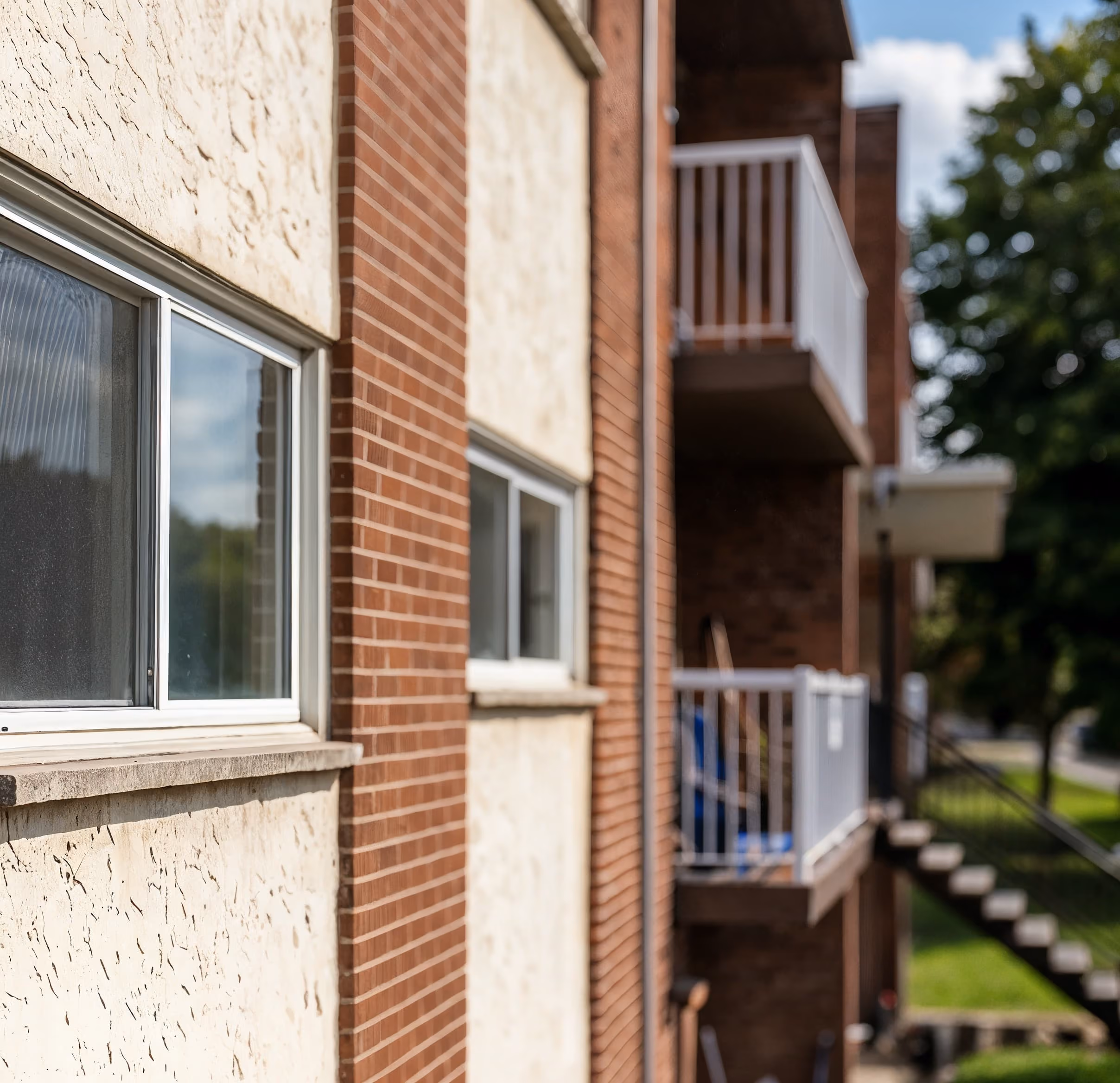 Close-up of a brick and stucco apartment building exterior with windows and balconies.