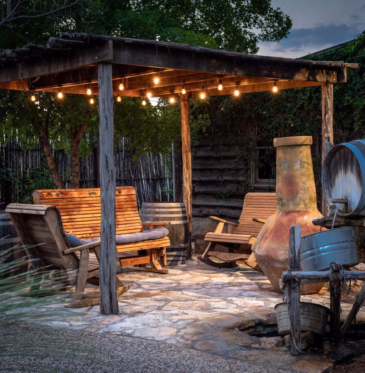 Cozy outdoor patio with rocking chairs, string lights, and rustic chiminea