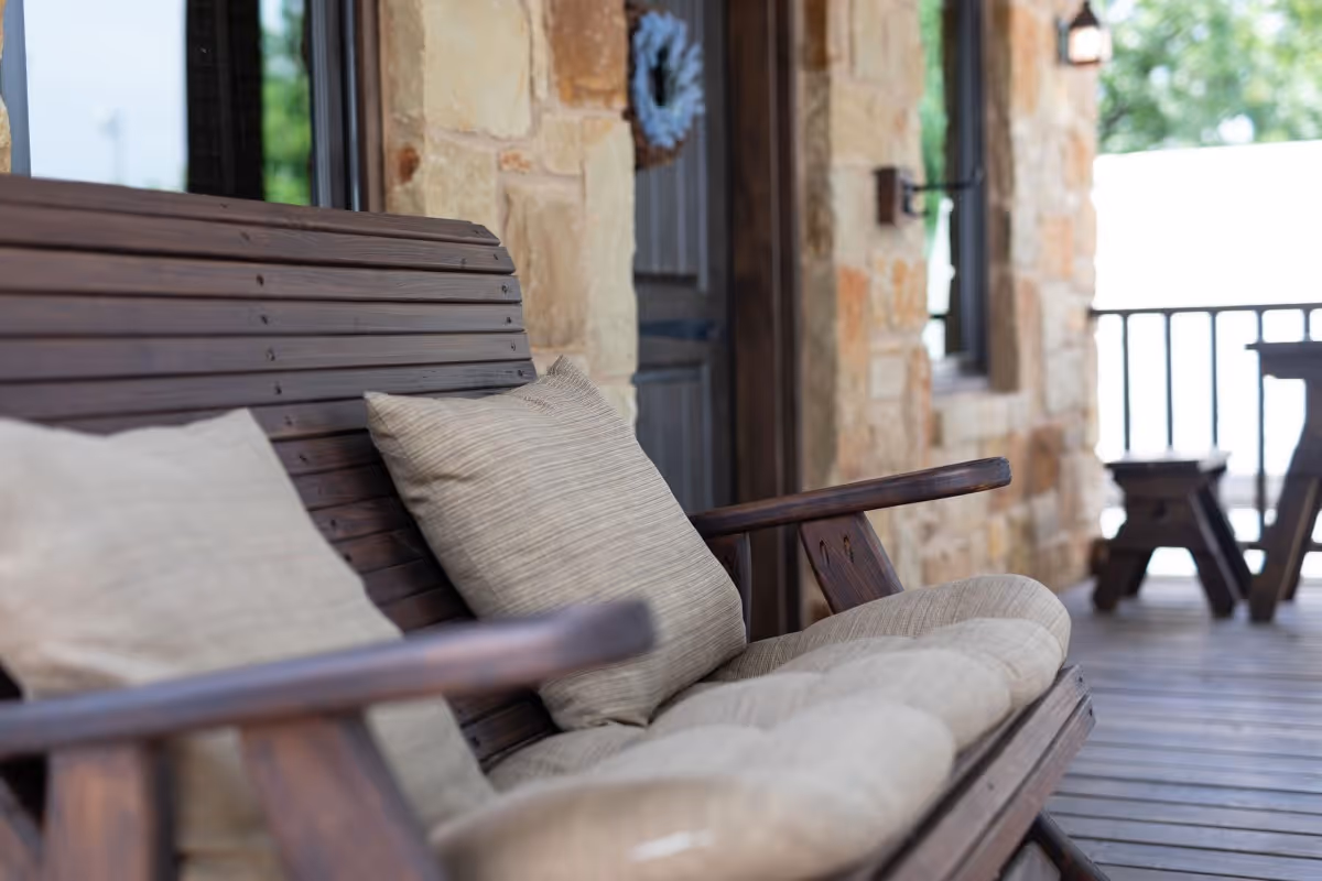 Cozy wooden bench with soft cushions on a rustic stone porch