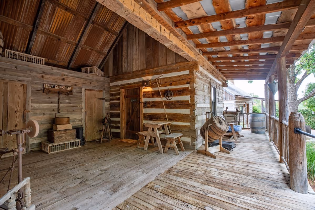 Rustic wooden barn interior with tools, wooden chairs, and porch