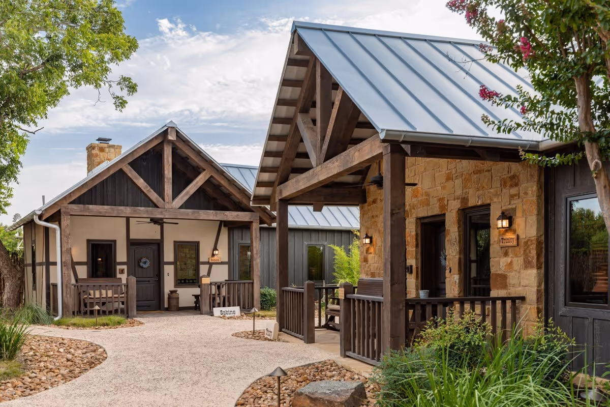 Rustic stone cabins with metal roofs and wooden porches in landscaped setting