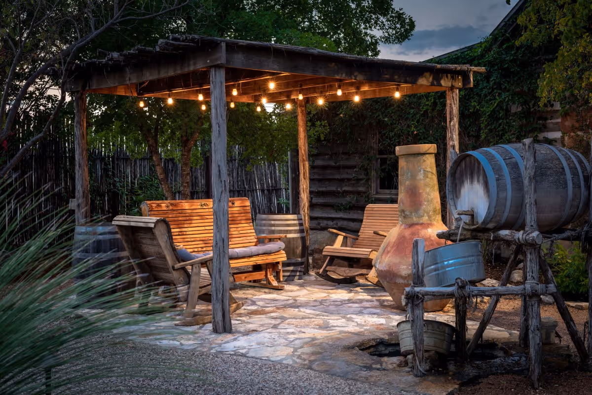 Cozy outdoor seating area with string lights, wooden chairs, and wine barrels