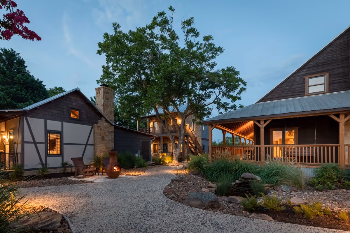 Twilight view of rustic wooden cabins with landscaped rocky garden
