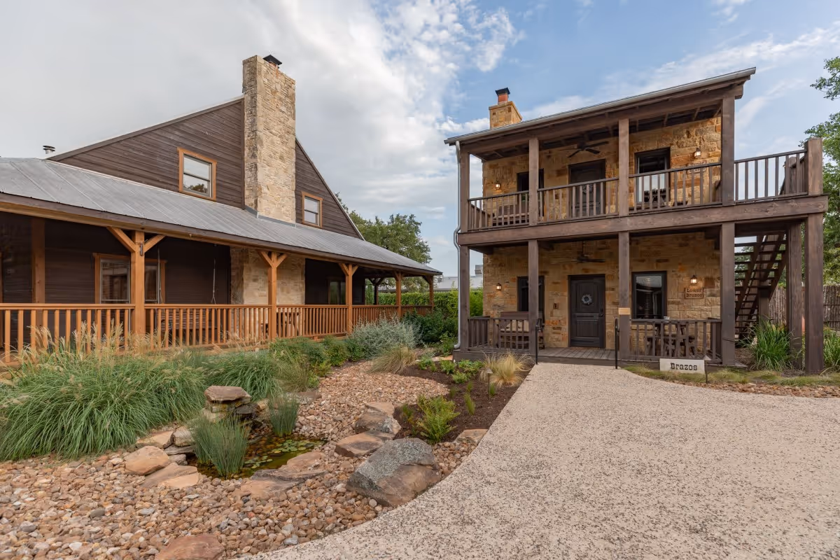 Stone and wood cabins with rock garden and stream on sunny day