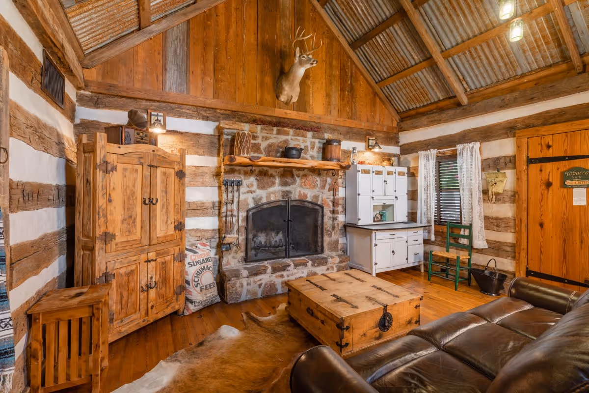 Rustic log cabin interior with stone fireplace, deer mount, and leather furniture