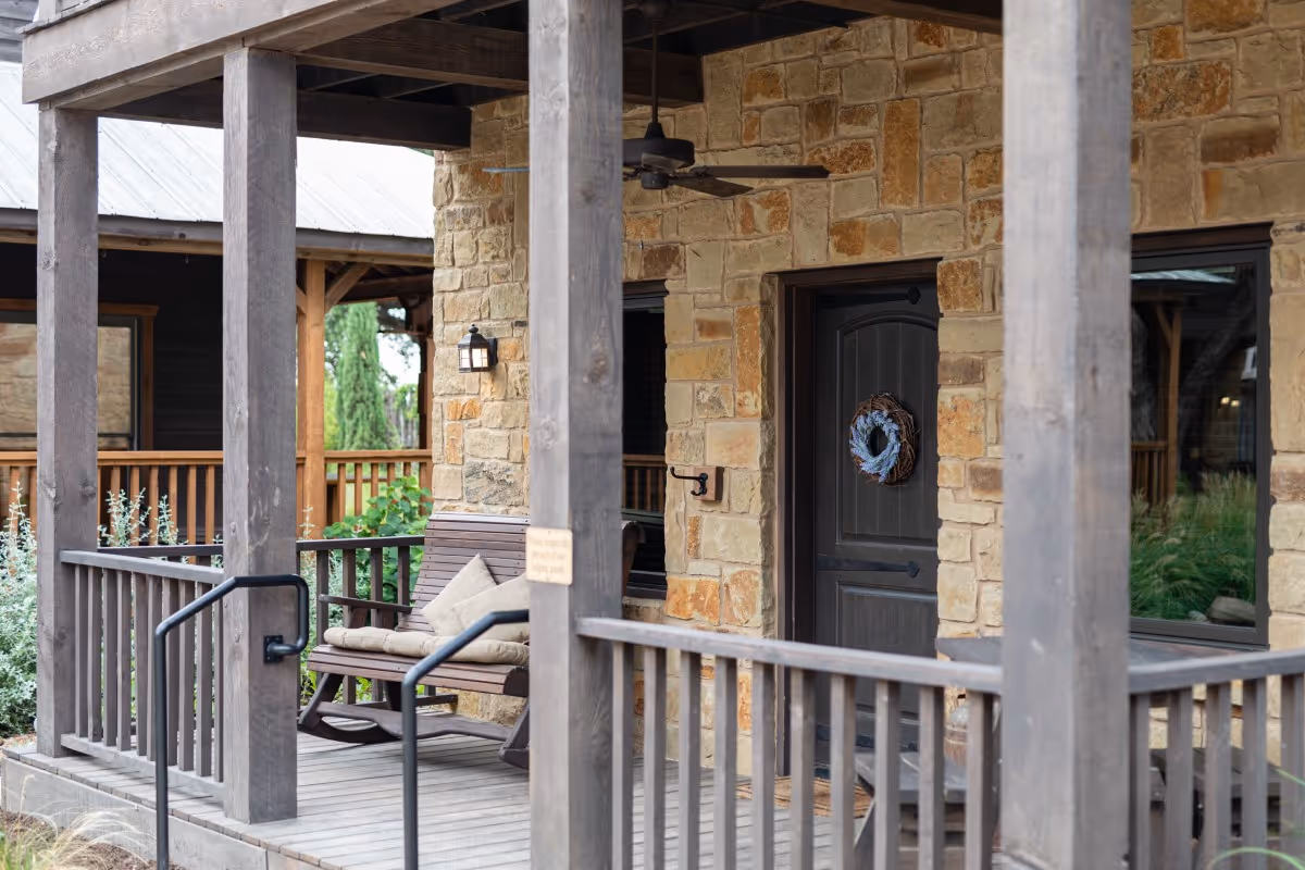 Rustic stone front porch with rocking chair and wreath on black door