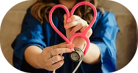 SmartCare RX Pharmacy staff member holding a pink stethoscope shaped like a heart, emphasizing compassionate healthcare.