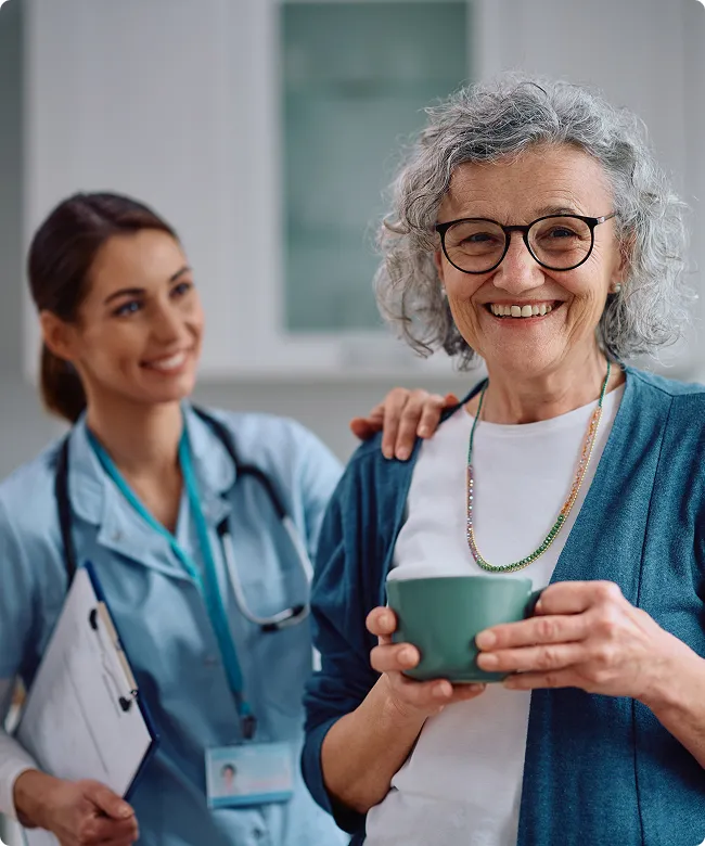 SmartCare Rx Pharmacy nurse supporting an elderly woman holding a mug, emphasizing compassionate home healthcare