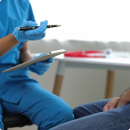 SmartCare Rx Pharmacy healthcare provider in blue scrubs consulting with a patient, taking notes during an appointment