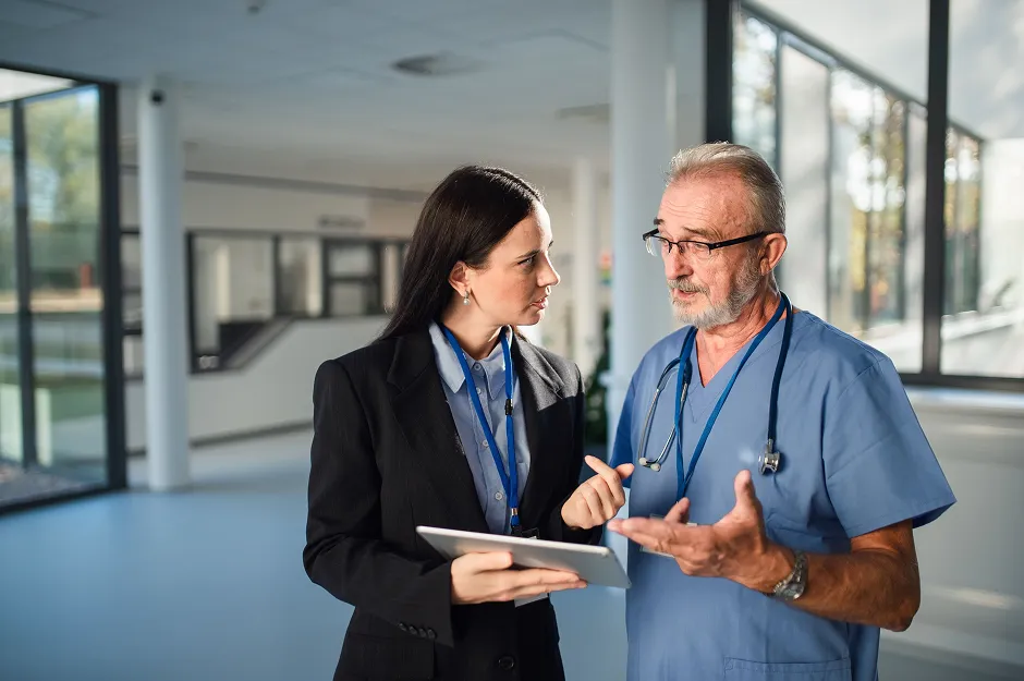 SmartCare Rx Pharmacy healthcare administrator discussing patient care with a senior physician in a hospital corridor