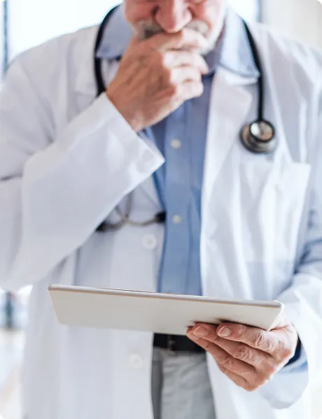 SmartCare Rx Pharmacy senior male doctor in a white coat thoughtfully reviewing patient information on a digital tablet, highlighting experience and modern healthcare technology