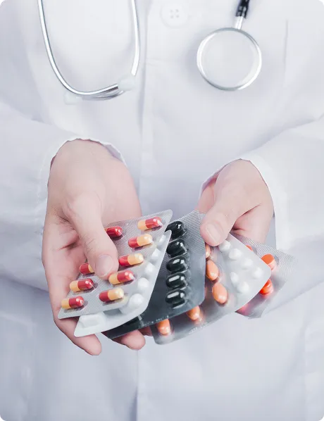 SmartCare Rx Pharmacy doctor in a white coat holding several blister packs of assorted colorful pills and capsules, highlighting professional medication management and pharmaceutical care.