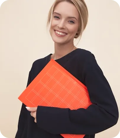 Young woman smiling, wearing black outfit and holding bright orange clutch.