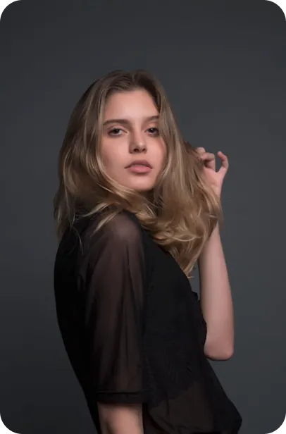 Young woman with long brown hair wearing black shirt against gray background