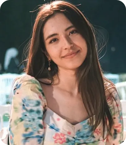 Young woman with long dark hair smiling in floral patterned shirt