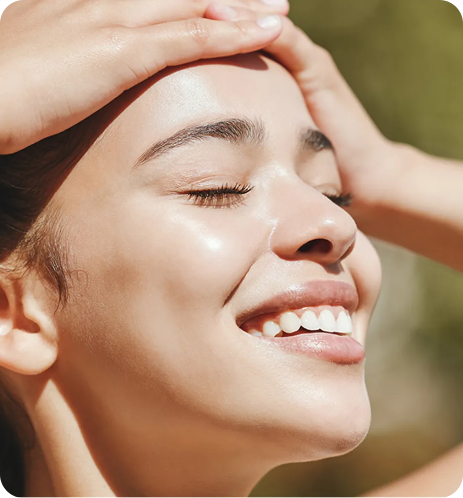 Woman smiling outdoors in sunlight.