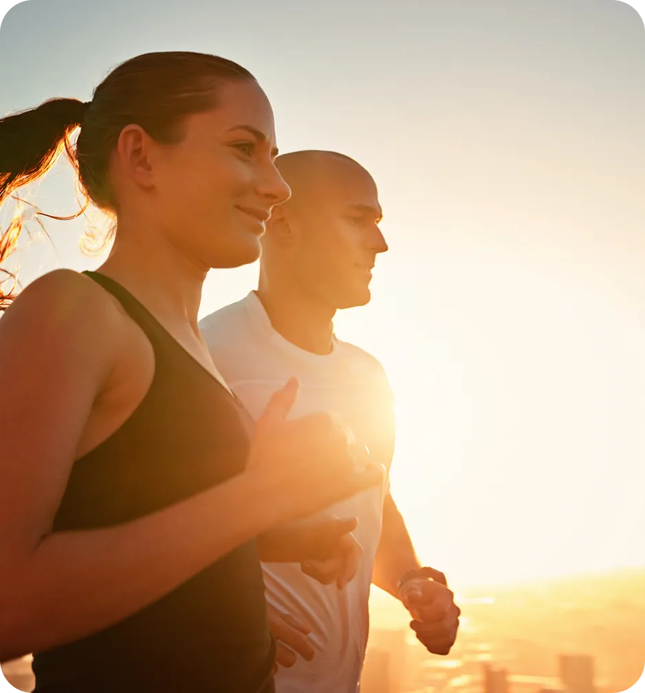 Two runners jogging together at sunset with warm golden light.