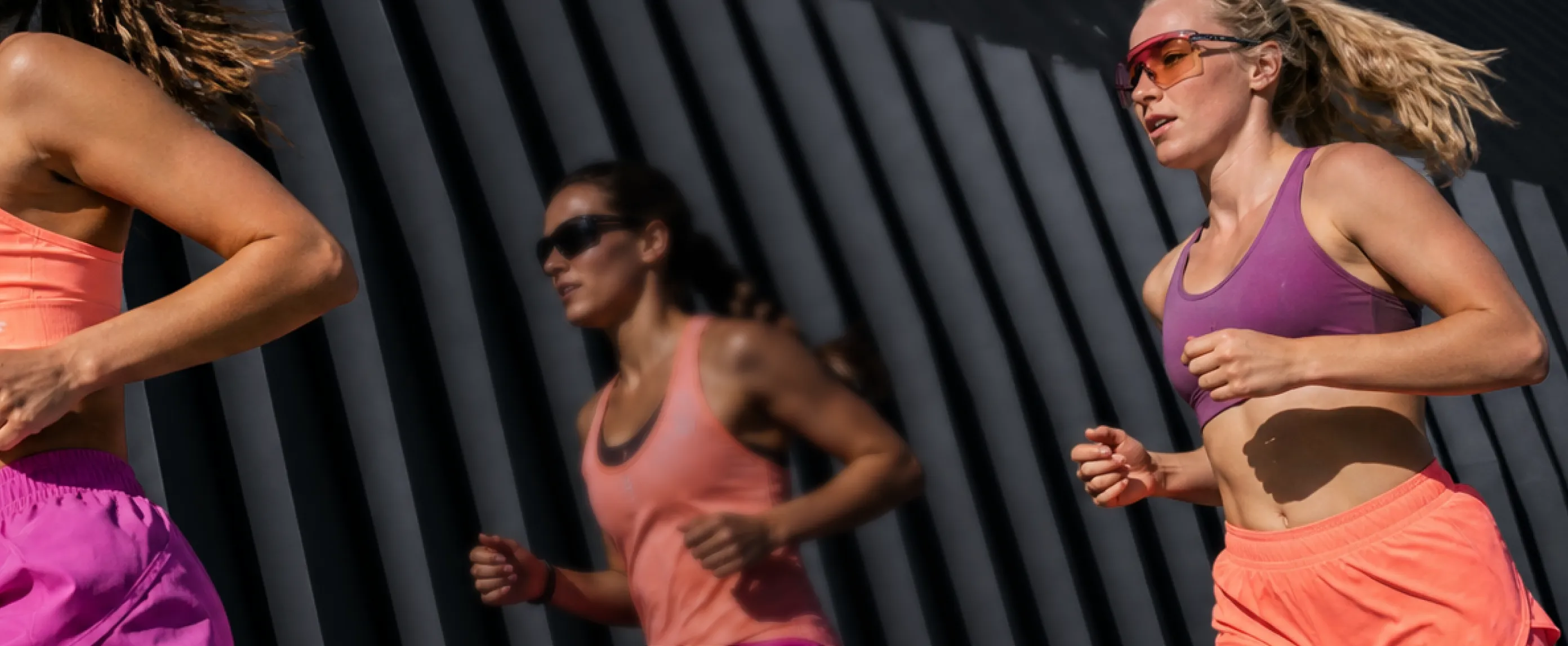 Three athletes running outdoors wearing colorful sports apparel and sunglasses