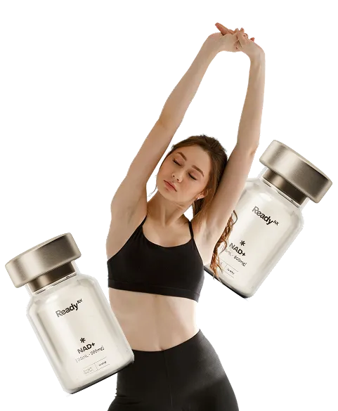 Woman in sports bra stretching arms up while holding supplement bottles