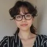 Portrait of a person with dark wavy hair, glasses, and striped shirt