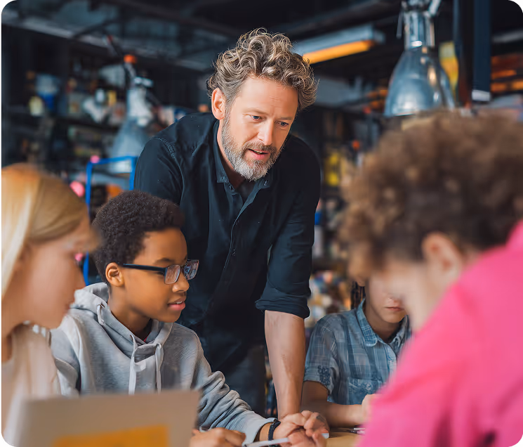 Teacher mentoring diverse students in STEM classroom with hands-on learning