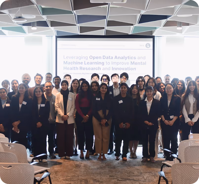 Group of diverse young adults posing together in a conference room in front of a presentation screen about open data analytics and machine learning for mental health research.