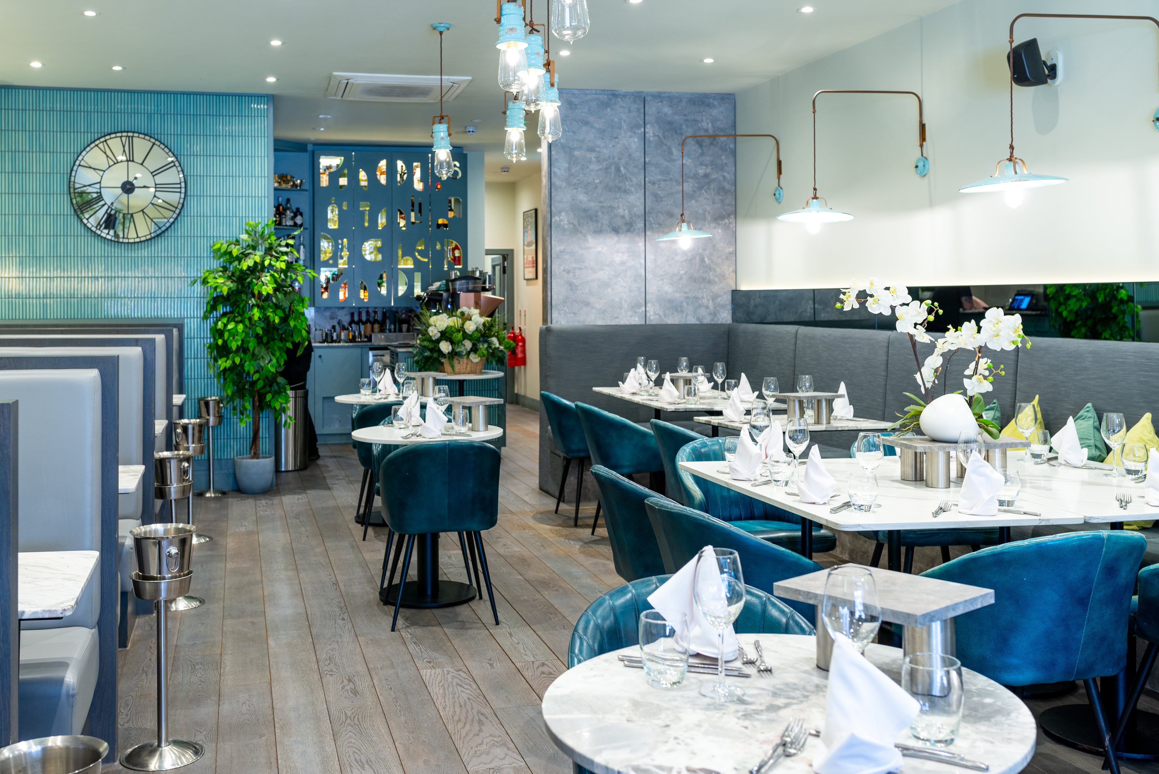 Modern interior of Paolo’s Italian Kitchen — elegant marble tables set with glassware and folded napkins, teal leather chairs, and soft lighting, creating a stylish and welcoming dining atmosphere.