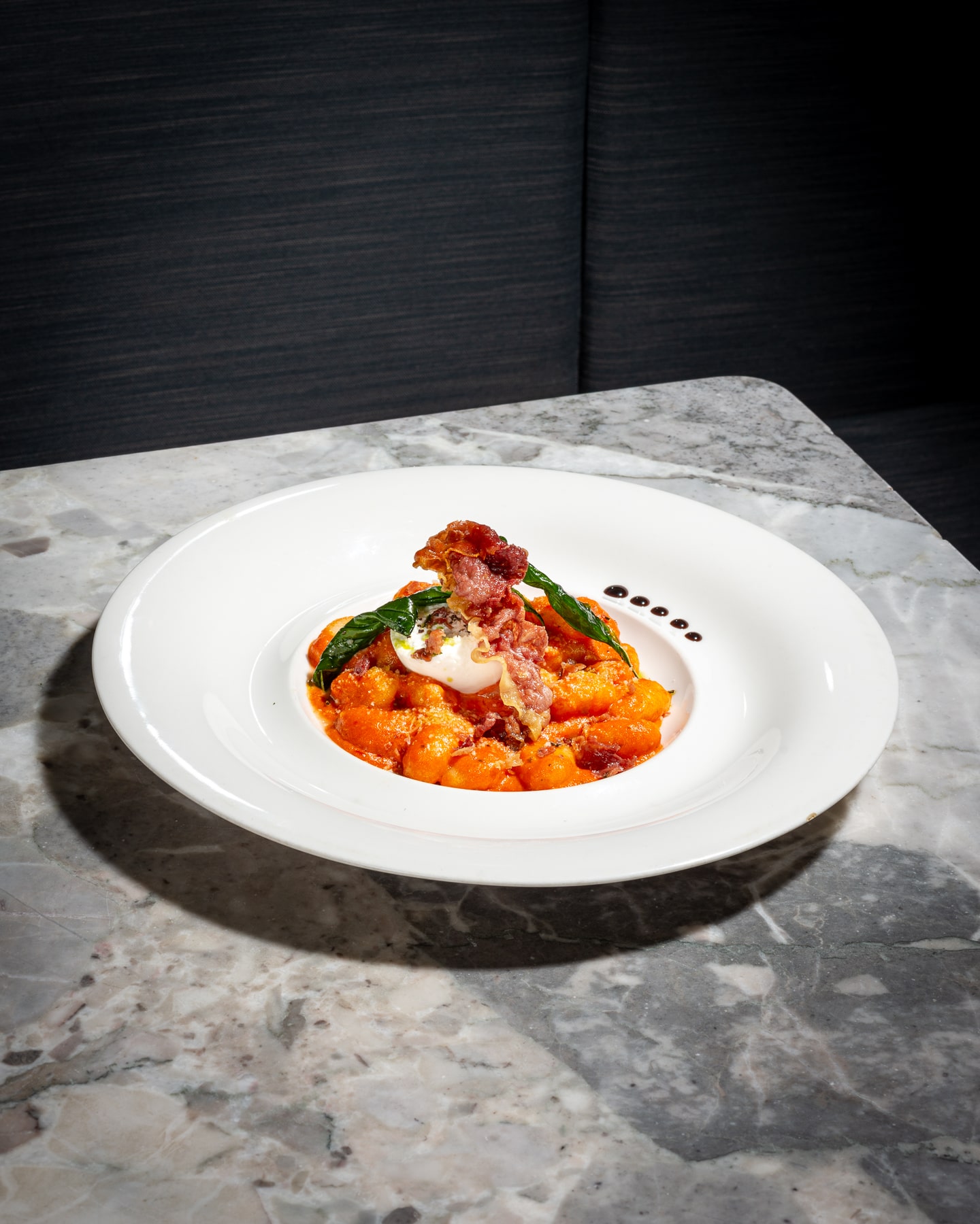Delicate potato gnocchi in a rich tomato sauce, topped with crispy pancetta, fresh basil, and a dollop of creamy cheese at Paolo’s Italian Kitchen.