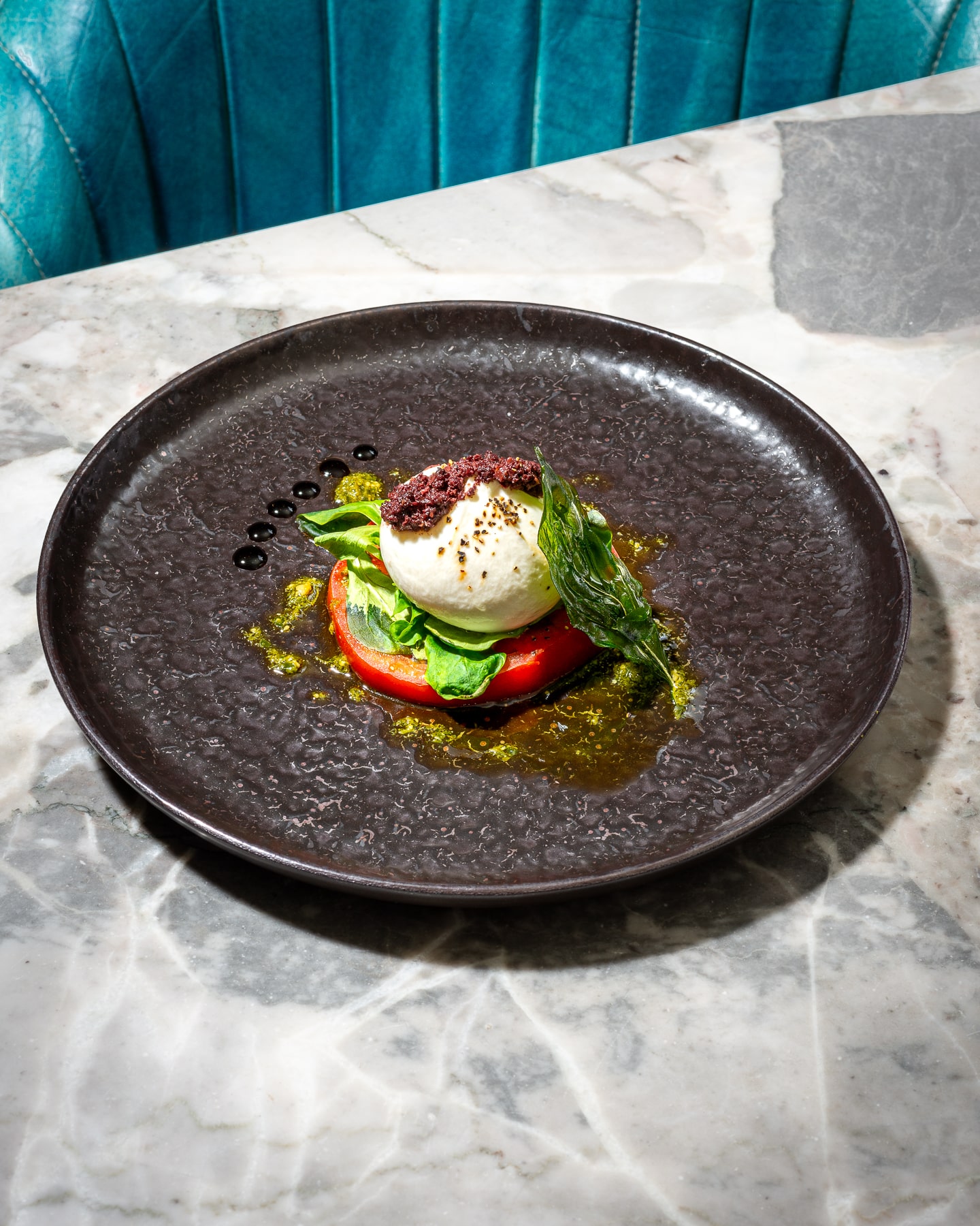 Elegant burrata starter at Paolo’s Italian Kitchen — creamy burrata served with fresh tomato, basil, olive oil, and a touch of black olive tapenade.