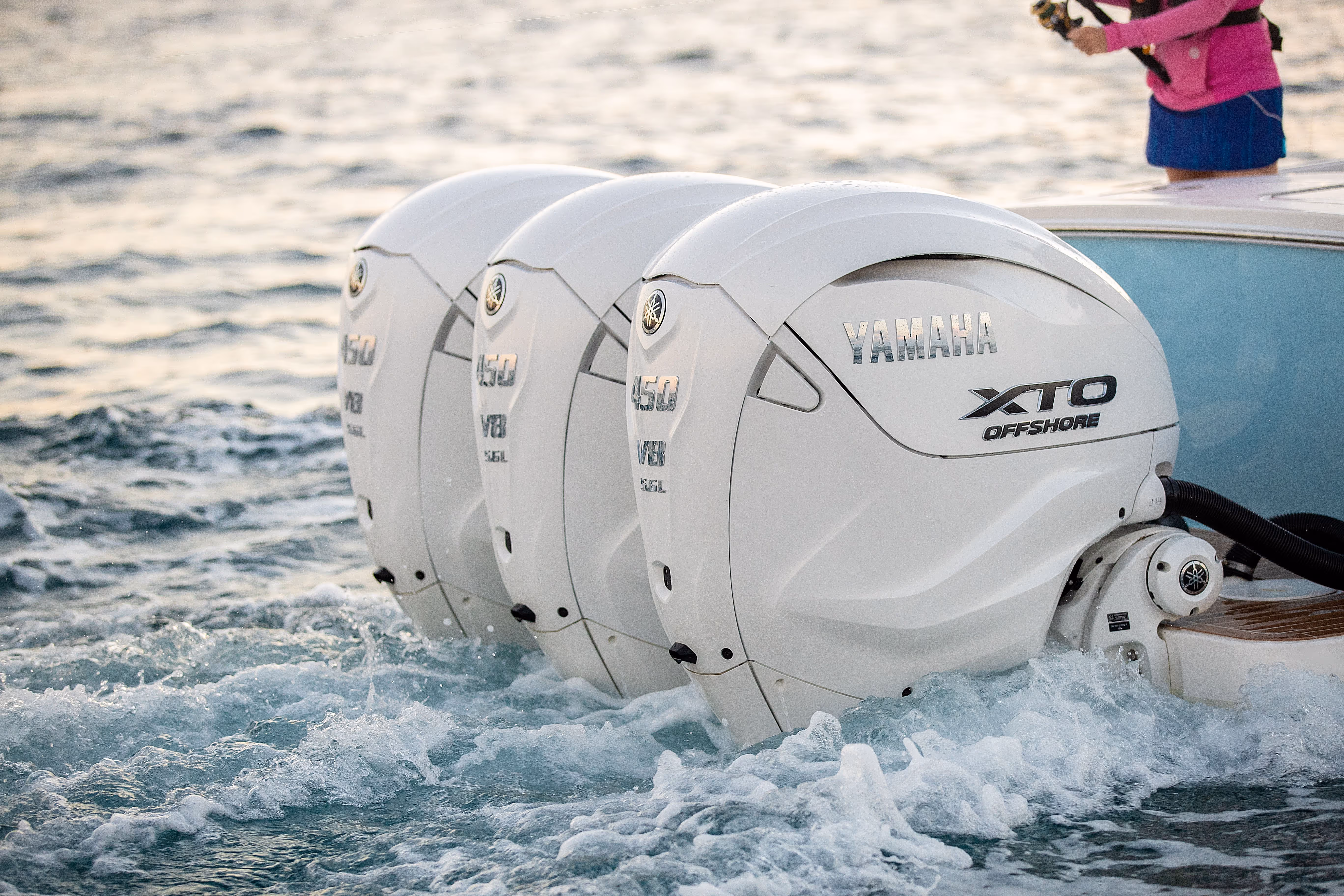 Three white Yamaha XTO Offshore 450 V8 outboard boat engines in the water creating waves.