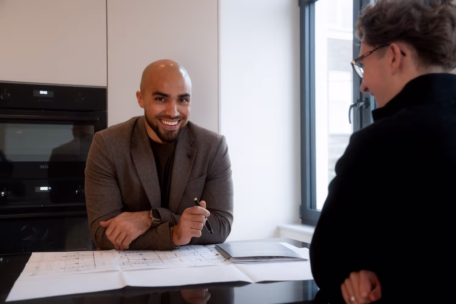 Agent and client going through floor plans on a kitchen counter