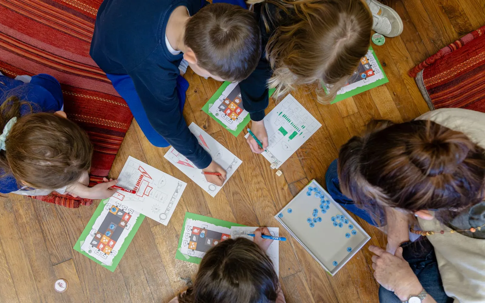 Enfants et adulte assis au sol jouant à un jeu de société