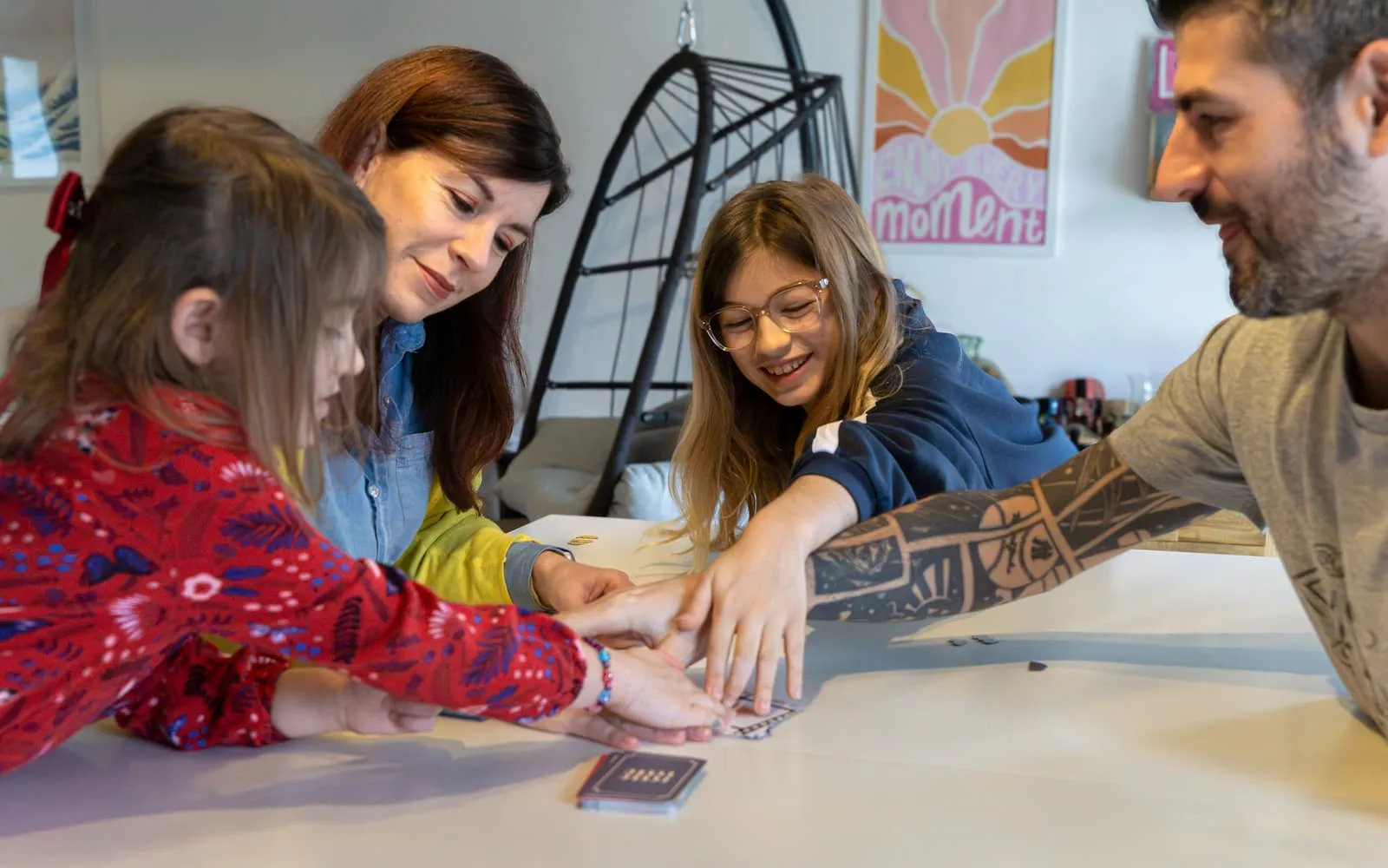 Famille jouant à un jeu de cartes ensemble autour d'une table blanche.