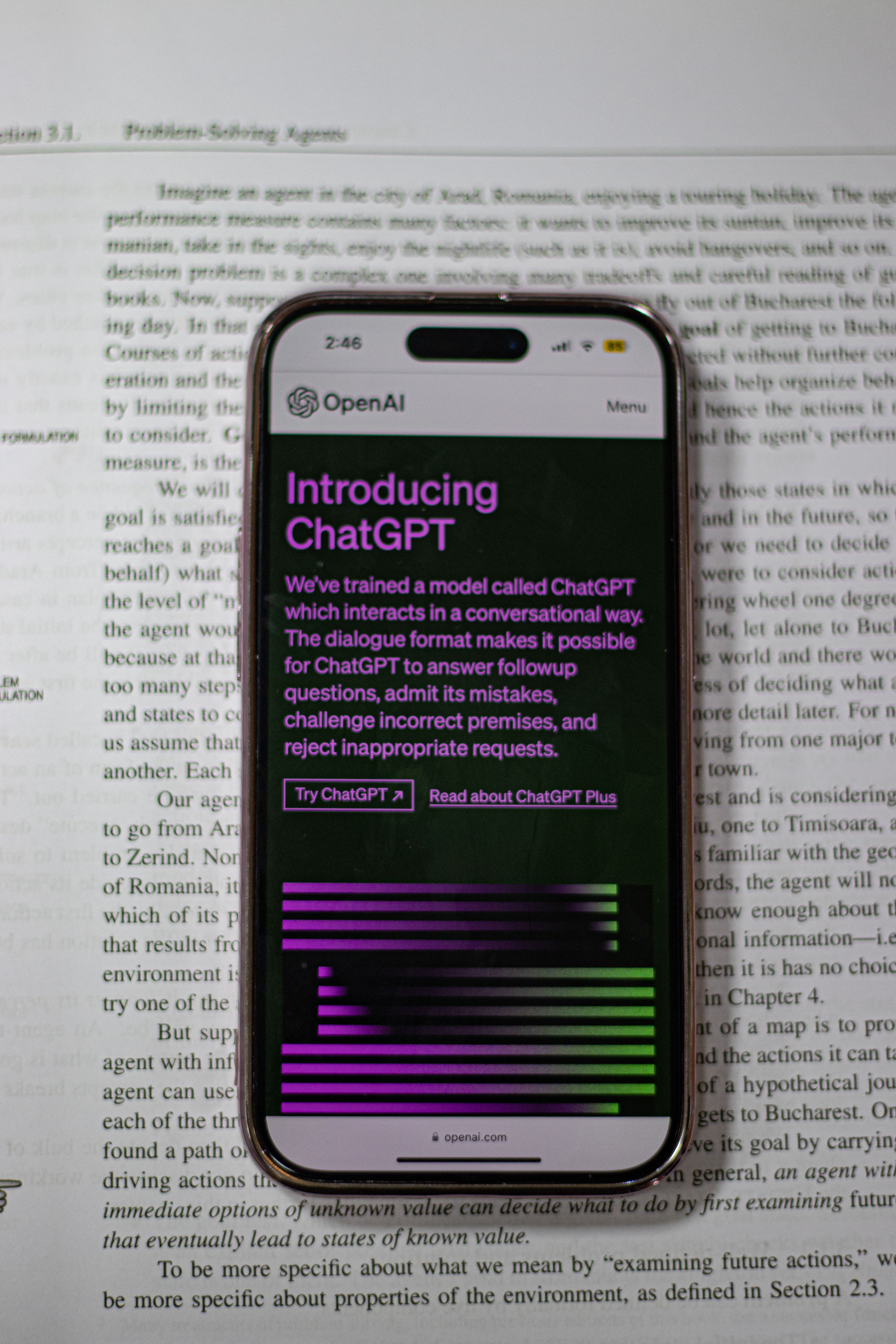 Phone displaying ChatGPT laying on top of an open book