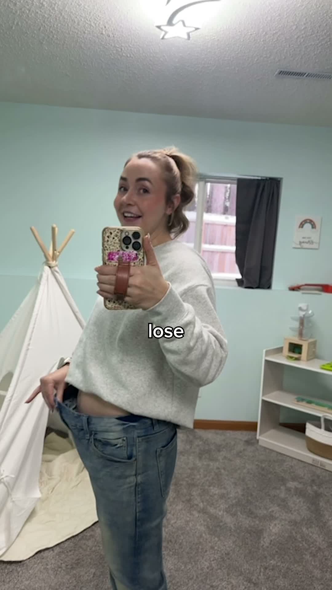 Woman taking selfie in bedroom holding phone with decorative case and teepee