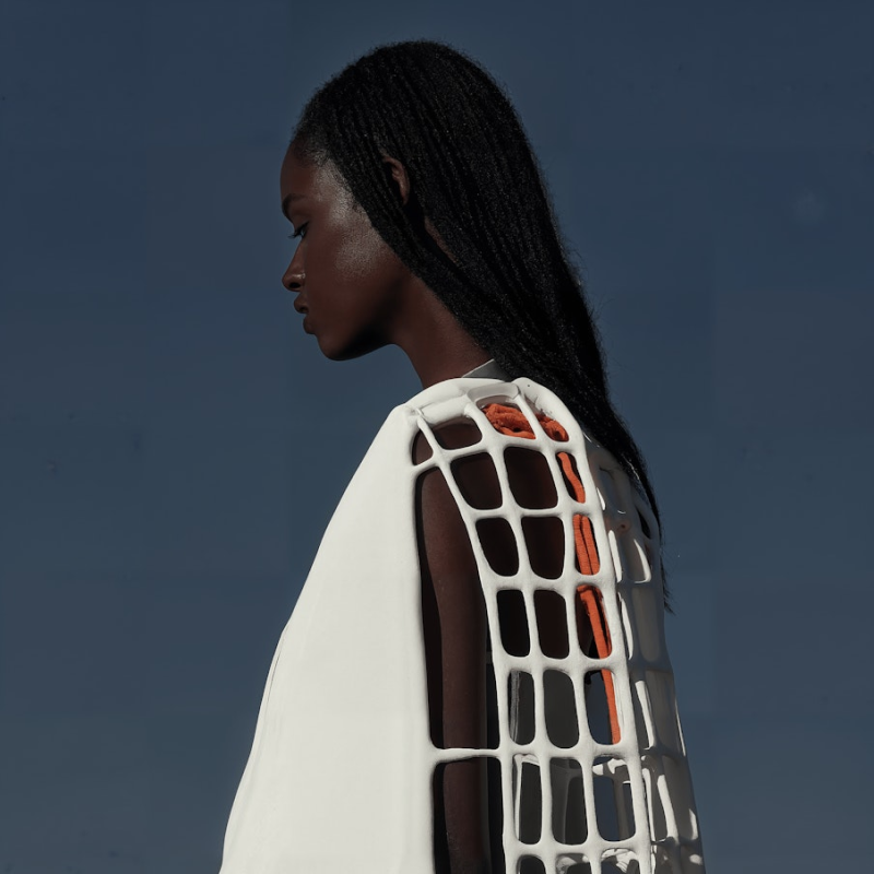 A woman in a white shirt with a black and orange design on it.
