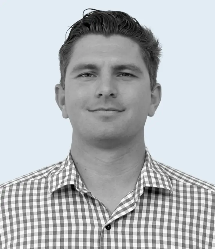 Headshot of a man with short dark hair wearing a checkered button-up shirt against a light background.
