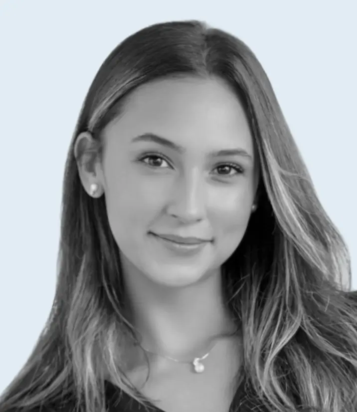 Portrait of a young woman with long straight hair, wearing pearl earrings and a necklace, smiling softly.