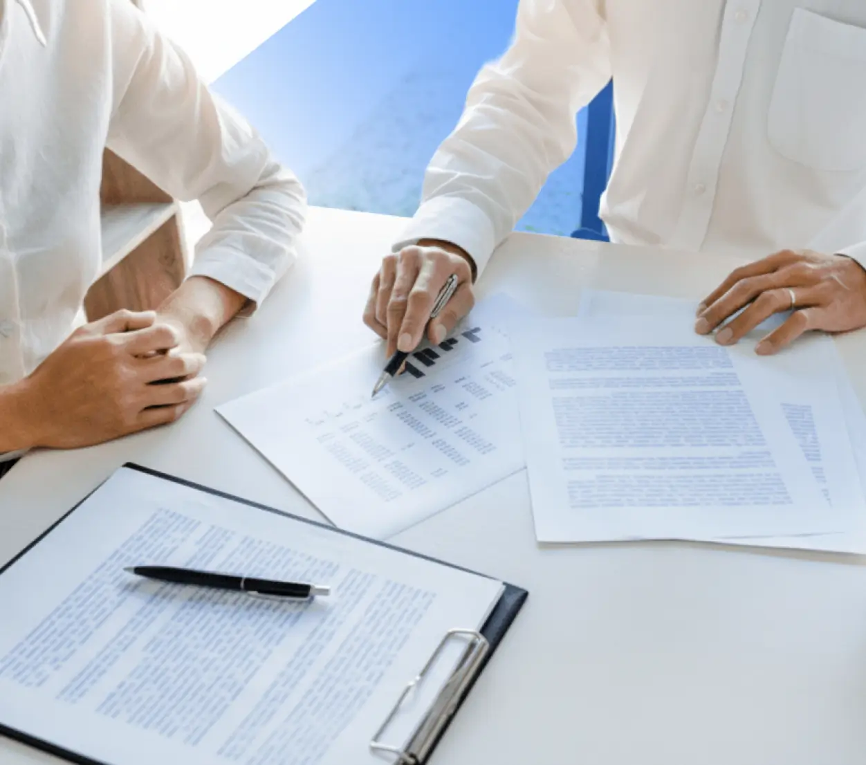 Two construction professionals wearing hard hats inspecting a modern house exterior on a sunny day, one holding blueprints.
