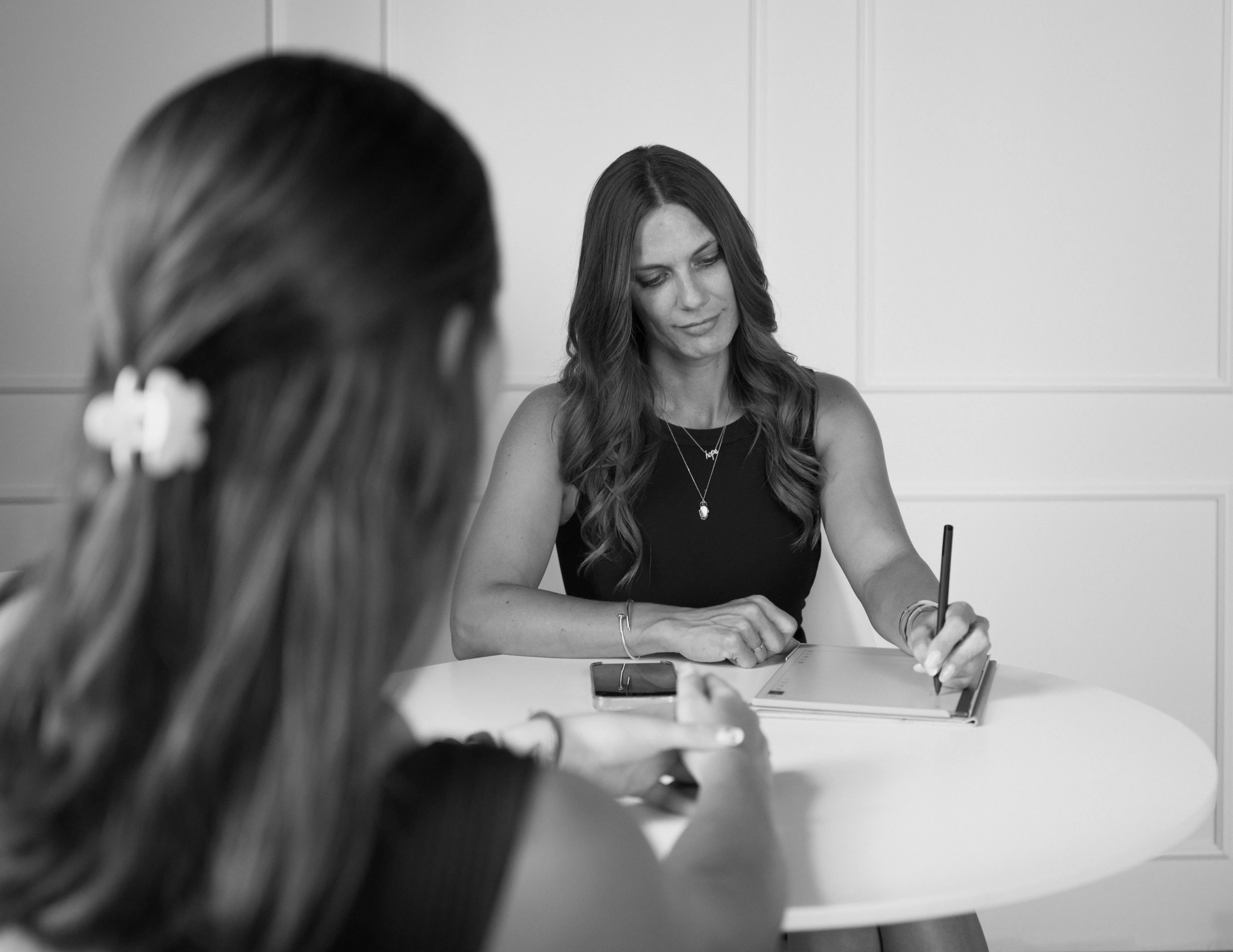 Kim Abrams taking notes during a business discussion at a table.
