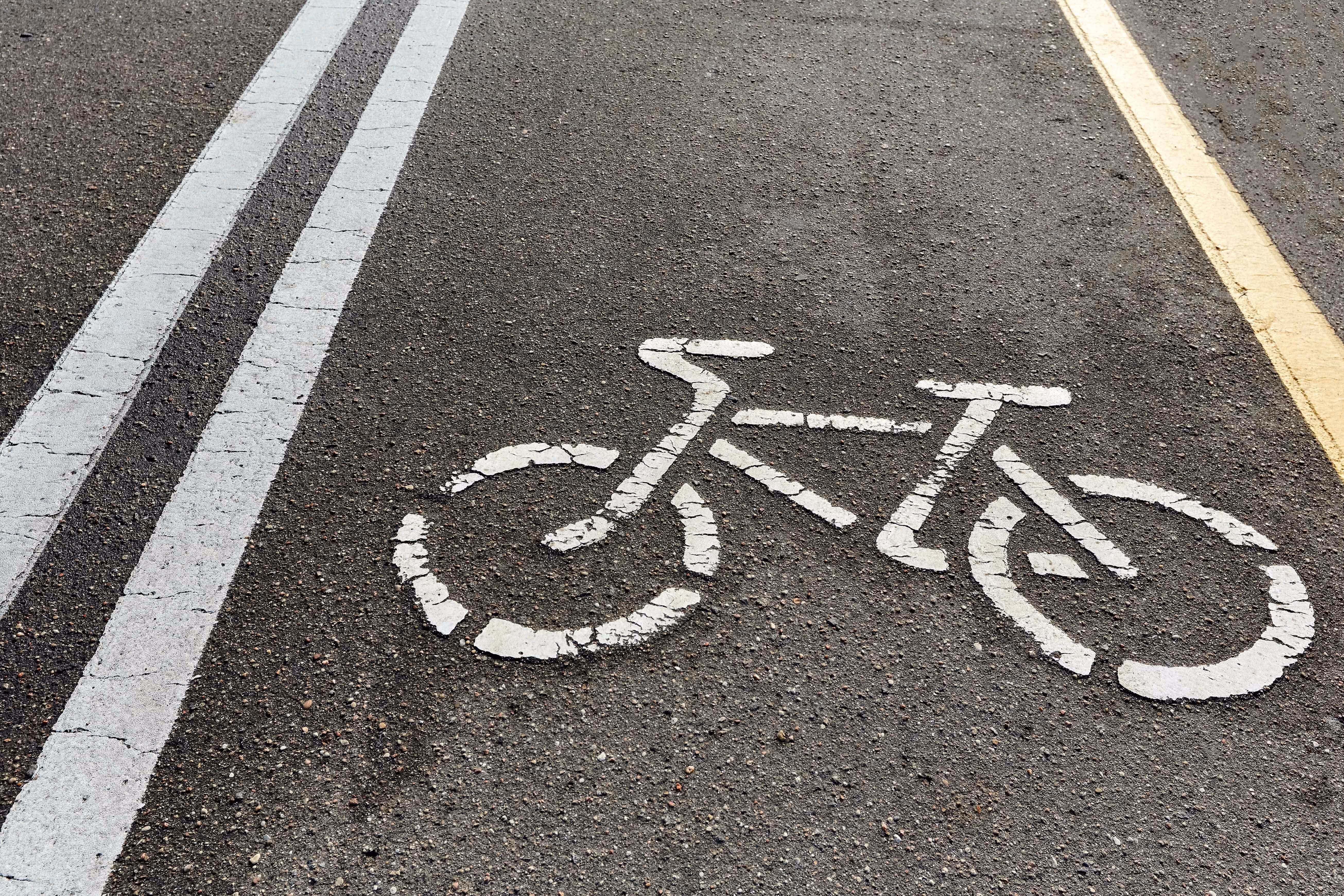 An up-close photo of the bike symbol for a bike lane on a road.
