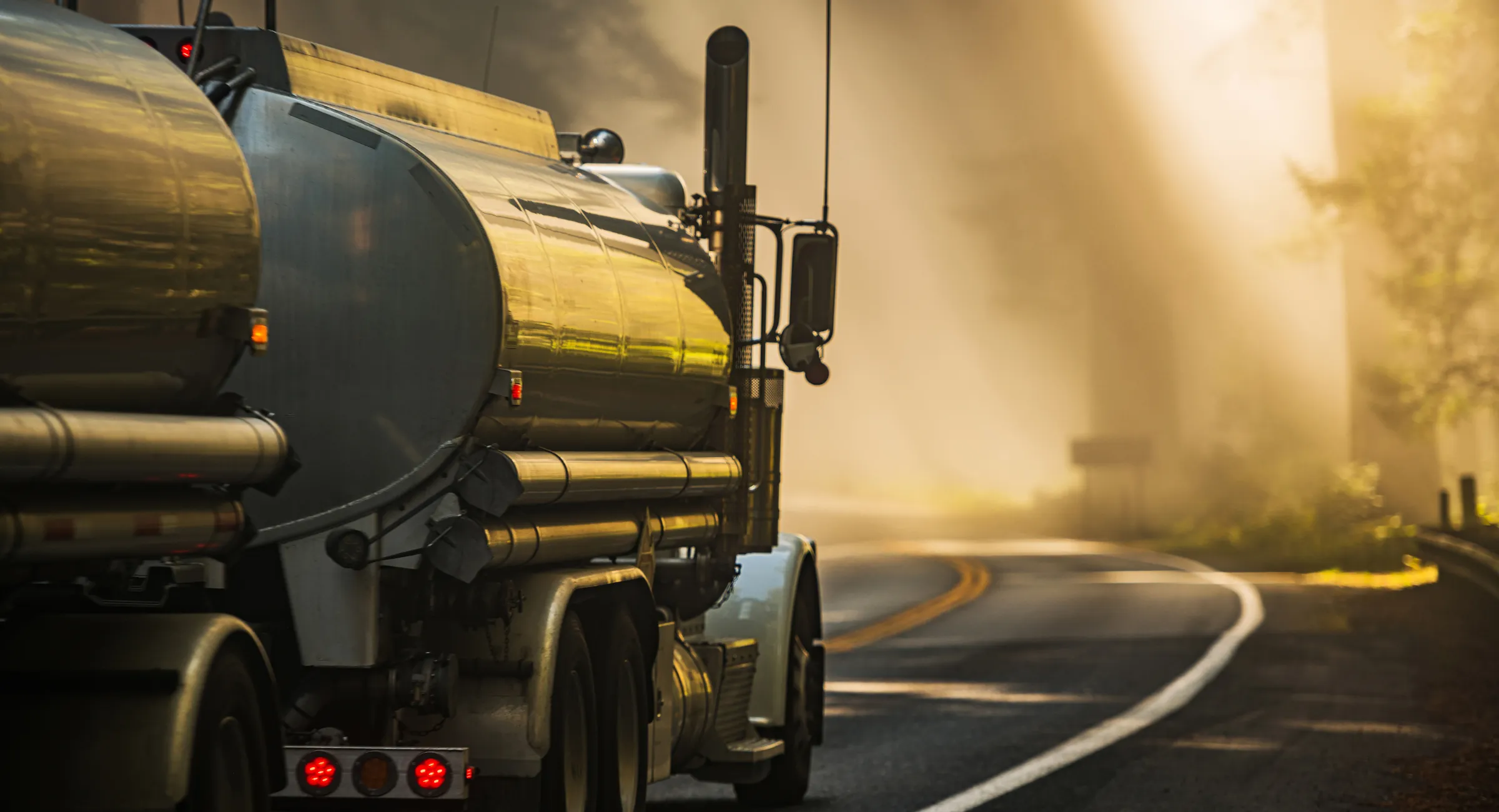 Tanker truck driving on a winding road at golden hour