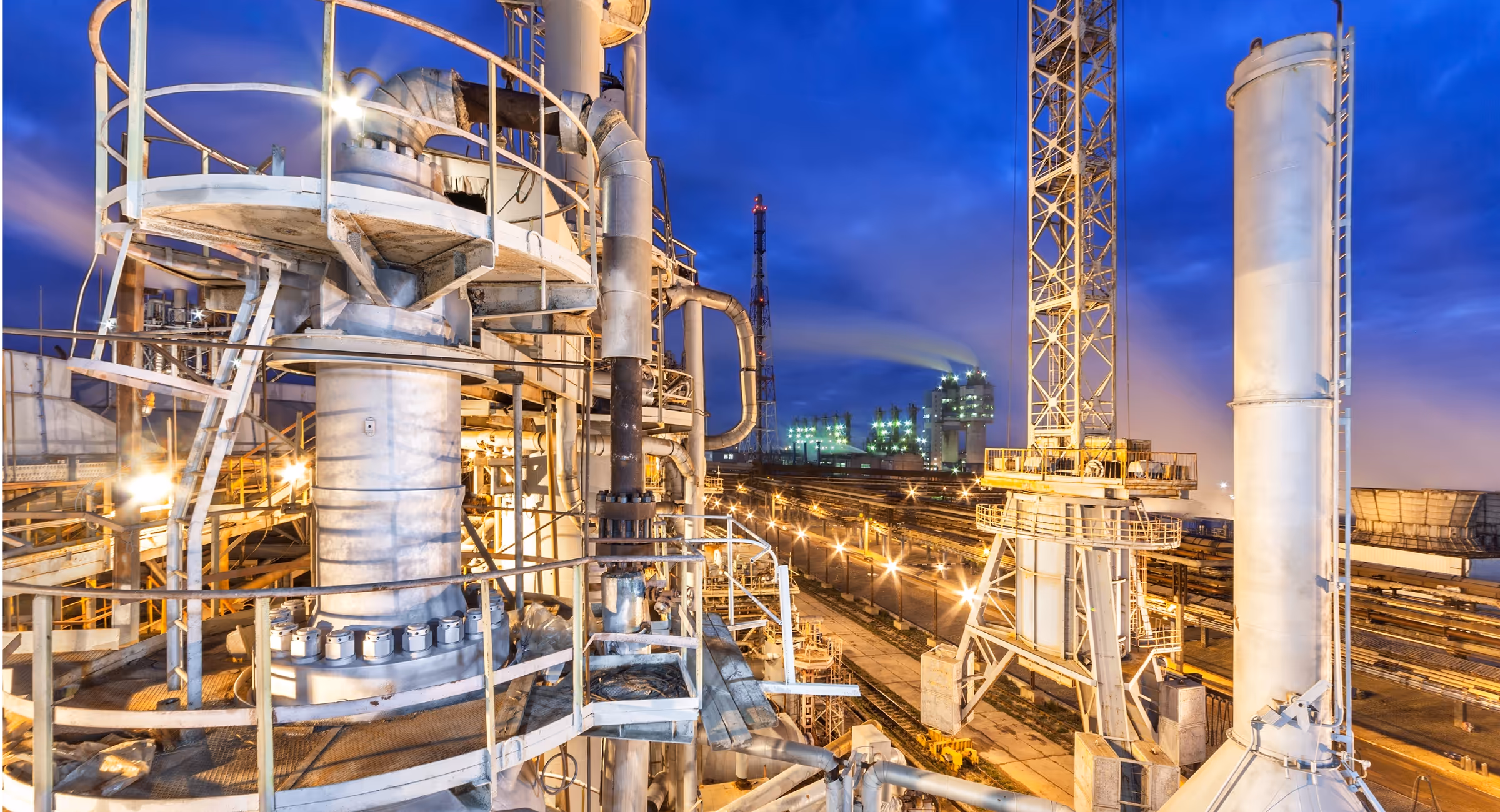 Industrial chemical plant with complex pipes and tanks at twilight