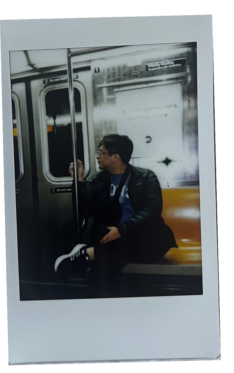 A polaroid picture of me taken on the New York City subway sitting on an orange seat.