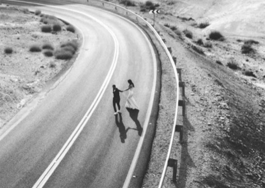  	Bride and groom walking on a winding desert road in Israel wedding photo