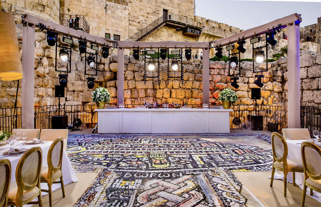 Elegant bar setup with lighting rig against ancient Jerusalem stone wall.