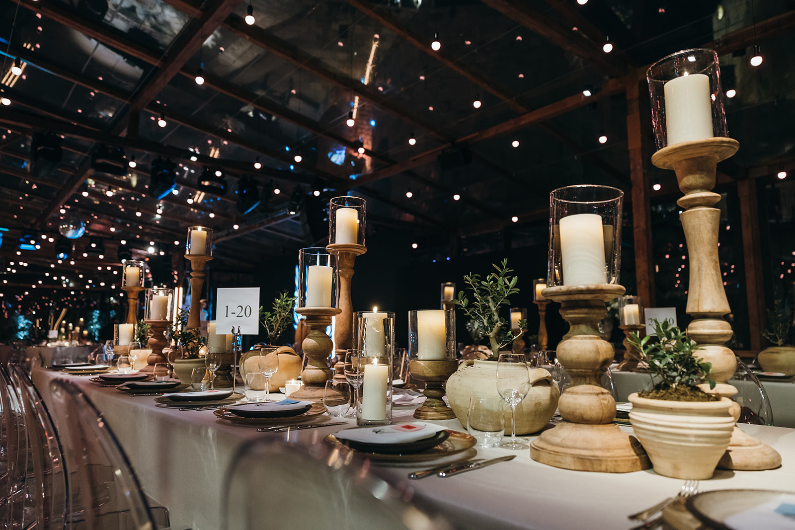 Candlelit long dinner table set under the stars, with transparent chairs and ancient Jerusalem stone walls visible.