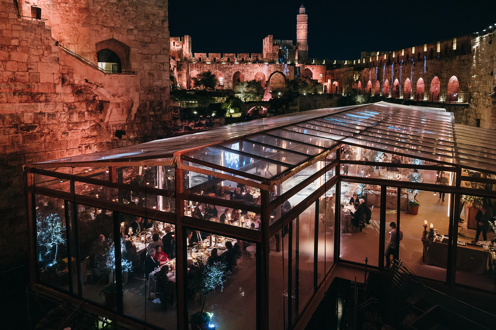 Night view of the Tower of David Museum with a glass-covered gala dinner setup beneath the ancient walls.
