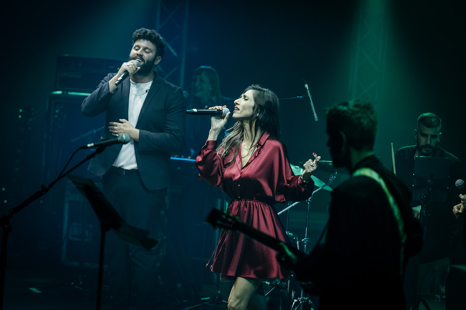 Female and male singers performing live on stage during the event’s musical performance.